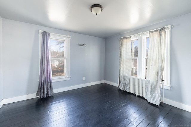 unfurnished room with dark wood finished floors, radiator, and baseboards