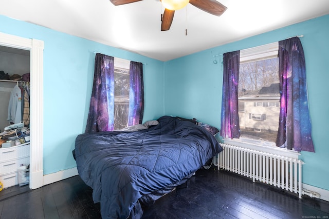 bedroom featuring radiator heating unit, a ceiling fan, baseboards, and wood-type flooring