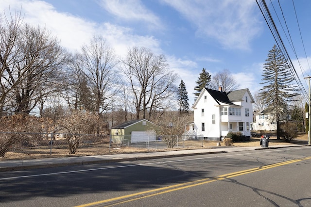 view of front of property featuring a fenced front yard, a residential view, a chimney, and an outdoor structure