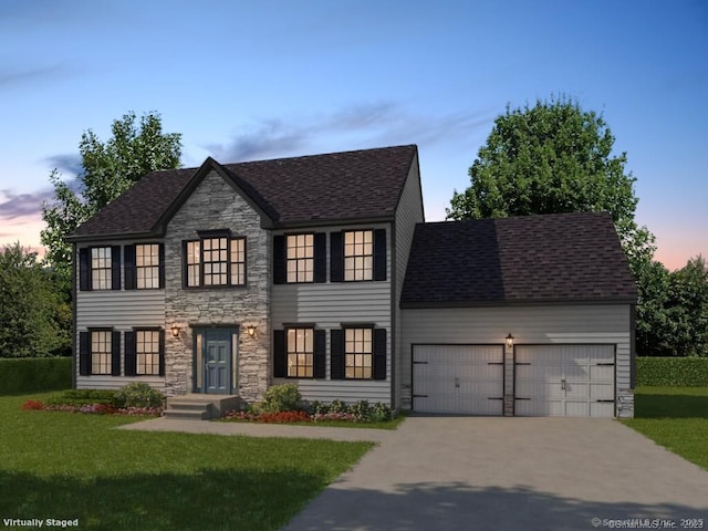 colonial inspired home with stone siding, a yard, driveway, and an attached garage