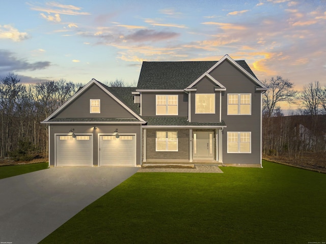 view of front of house featuring a lawn, driveway, a shingled roof, and a garage