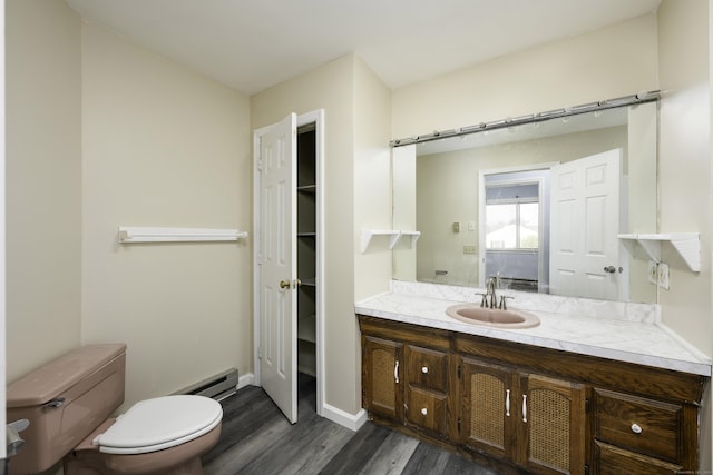 bathroom featuring toilet, a baseboard heating unit, wood finished floors, baseboards, and vanity