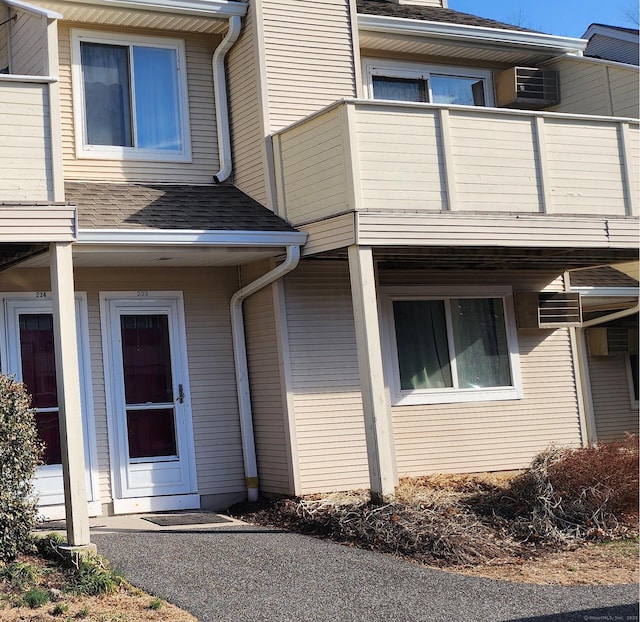 view of exterior entry featuring a balcony and a shingled roof