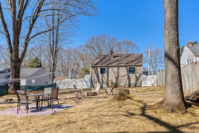 back of property with a fenced backyard, a lawn, a fire pit, and a patio