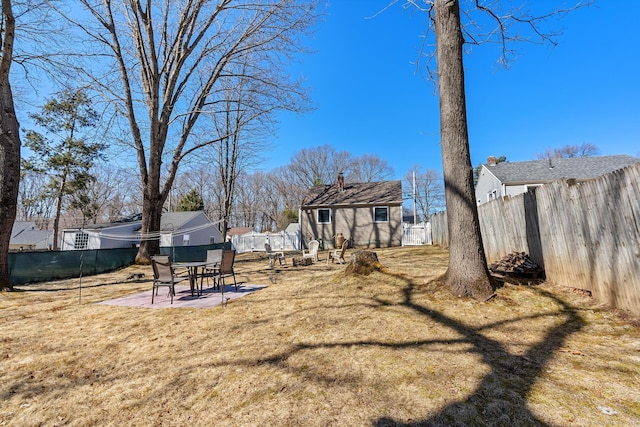 view of yard featuring a patio, a fenced backyard, and an outdoor structure