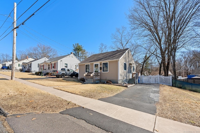 bungalow-style home with a residential view, driveway, and fence