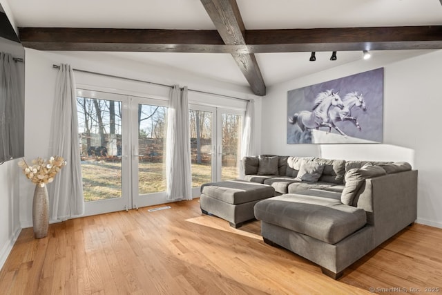 living area featuring beamed ceiling, light wood-style flooring, baseboards, and visible vents