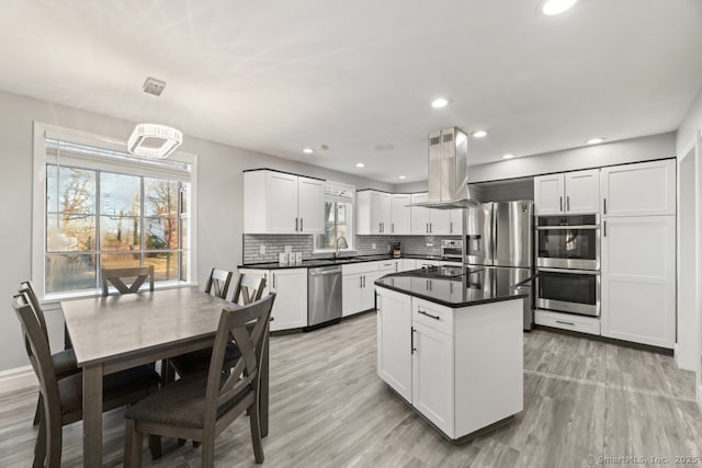 kitchen with a sink, dark countertops, tasteful backsplash, appliances with stainless steel finishes, and island range hood