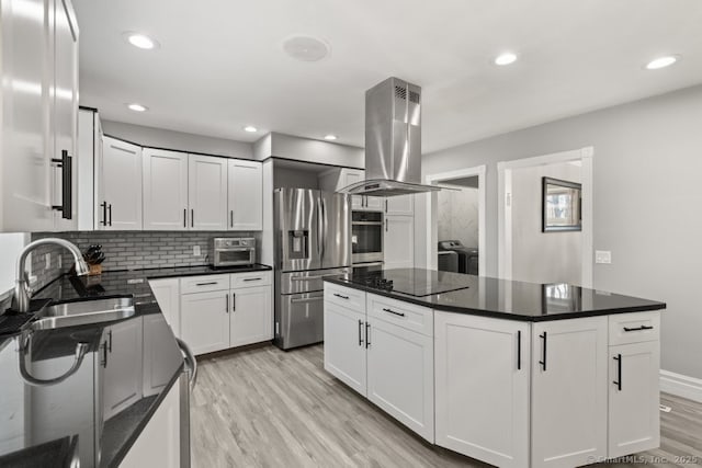 kitchen featuring a sink, light wood-style floors, appliances with stainless steel finishes, independent washer and dryer, and island range hood