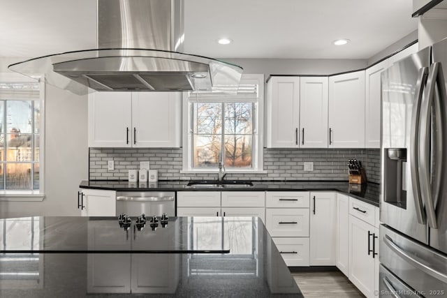 kitchen featuring a sink, white cabinets, appliances with stainless steel finishes, tasteful backsplash, and island range hood