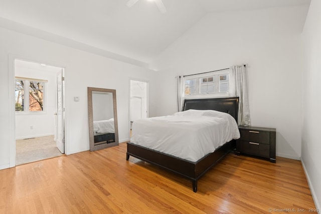 bedroom with light wood-type flooring, baseboards, high vaulted ceiling, and a ceiling fan