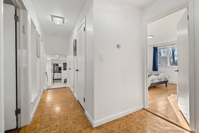 hallway featuring parquet flooring and baseboards