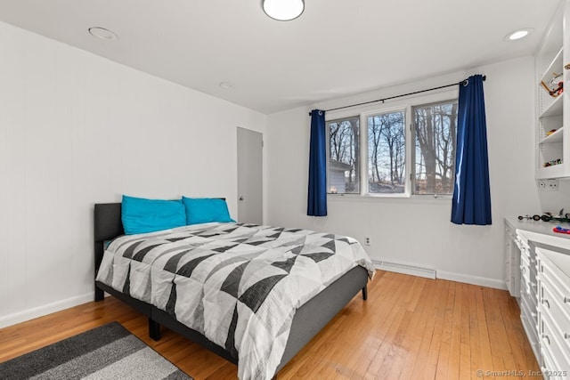 bedroom with light wood-style floors, baseboards, and baseboard heating