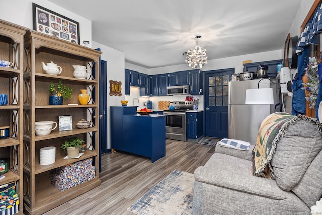 kitchen with a chandelier, appliances with stainless steel finishes, blue cabinets, and wood finished floors