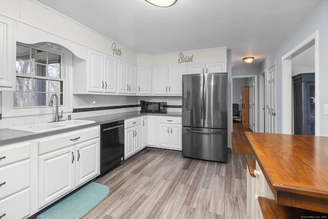 kitchen featuring a sink, black appliances, light wood-style floors, white cabinetry, and backsplash