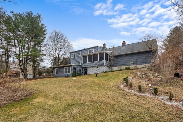 back of property featuring a chimney, a yard, and a sunroom
