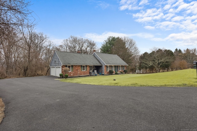 single story home with aphalt driveway, a front yard, a garage, brick siding, and a chimney