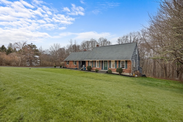 view of front of property with a front lawn, covered porch, brick siding, and a shingled roof