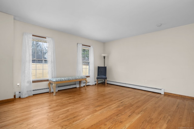 unfurnished room featuring light wood finished floors, baseboard heating, and baseboards