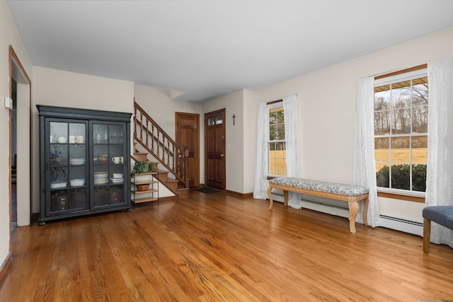 entryway featuring stairs, wood finished floors, baseboards, and a baseboard radiator