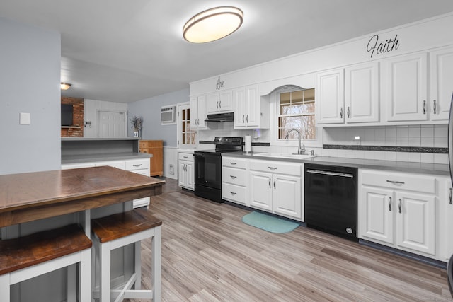kitchen with under cabinet range hood, white cabinets, black appliances, and tasteful backsplash