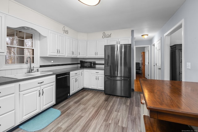 kitchen featuring light wood-type flooring, black appliances, a sink, tasteful backsplash, and white cabinetry