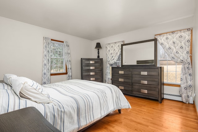 bedroom with a baseboard heating unit and wood finished floors