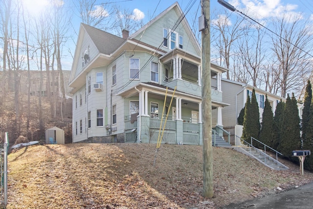 view of front facade with a shed, stairway, cooling unit, covered porch, and a chimney