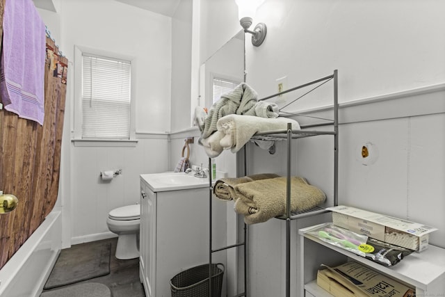 bathroom featuring vanity, toilet, shower / bath combo, and wainscoting