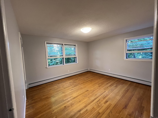 empty room with a baseboard radiator, a textured ceiling, and wood finished floors