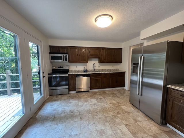 kitchen with a wealth of natural light, dark brown cabinets, appliances with stainless steel finishes, and a sink