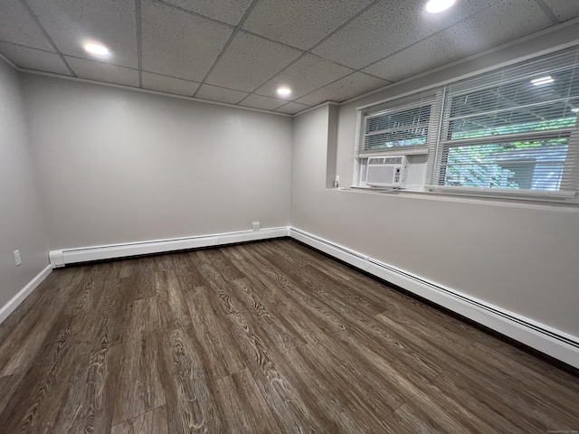 empty room with dark wood finished floors, cooling unit, a baseboard heating unit, and baseboards