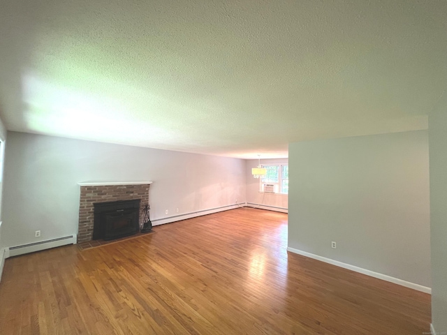 unfurnished living room featuring a baseboard heating unit, wood finished floors, baseboards, and a textured ceiling