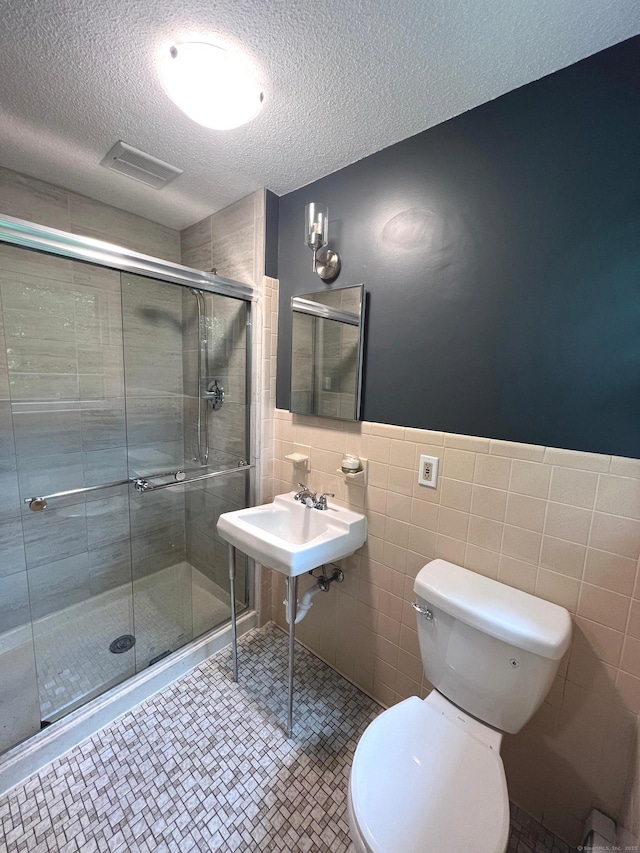 bathroom with visible vents, tile patterned flooring, a shower stall, a textured ceiling, and toilet