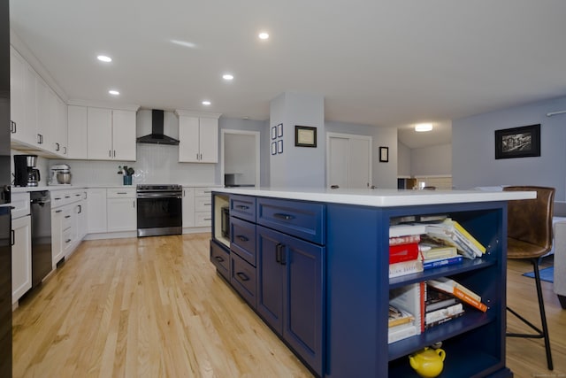 kitchen with blue cabinets, wall chimney range hood, electric range oven, light countertops, and dishwashing machine