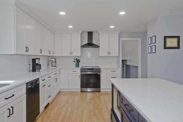 kitchen featuring wall chimney range hood, light wood-type flooring, black dishwasher, stainless steel range with electric stovetop, and white cabinets