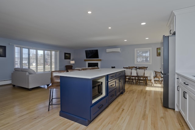 kitchen with a kitchen island, open floor plan, freestanding refrigerator, and a wall unit AC