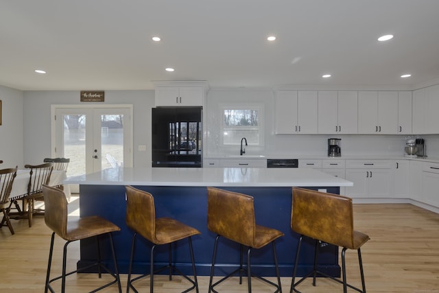 kitchen with french doors, light wood-type flooring, fridge, and a sink