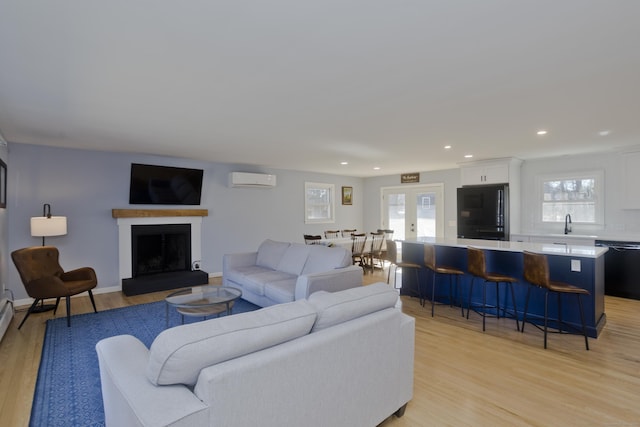 living room with baseboards, recessed lighting, a fireplace with raised hearth, french doors, and light wood-type flooring