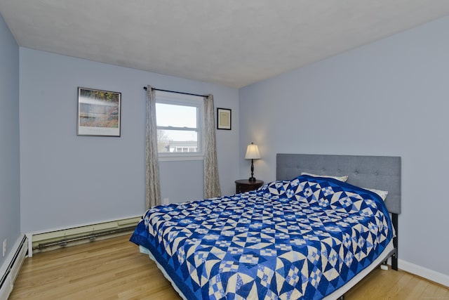 bedroom featuring wood finished floors, baseboards, and a baseboard radiator