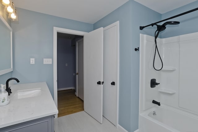 bathroom with tub / shower combination, vanity, and baseboards