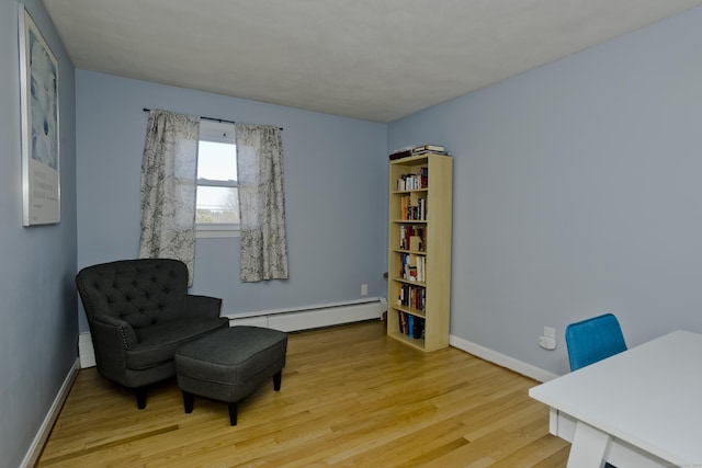 sitting room featuring light wood-type flooring, a baseboard radiator, and baseboards