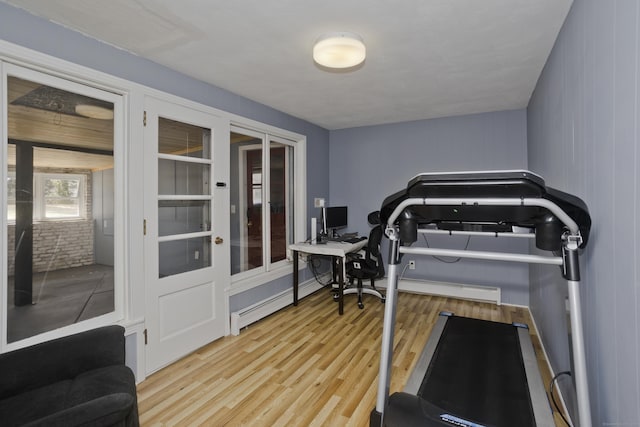 workout room featuring baseboard heating and wood finished floors