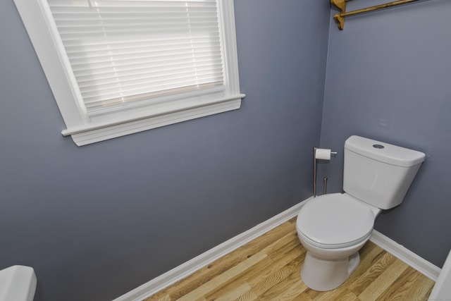 bathroom featuring toilet, baseboards, and wood finished floors