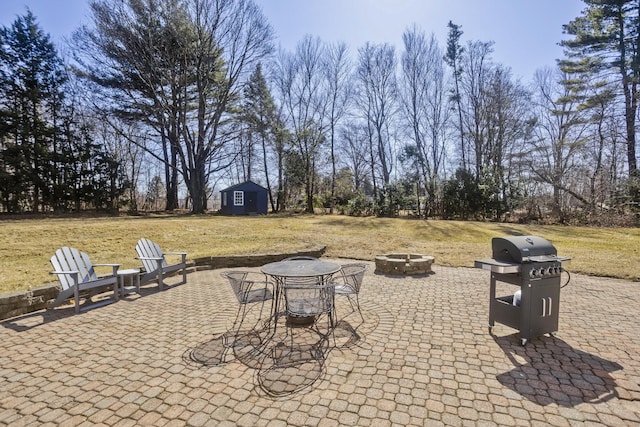 view of patio / terrace featuring an outdoor structure, a fire pit, a shed, and a grill