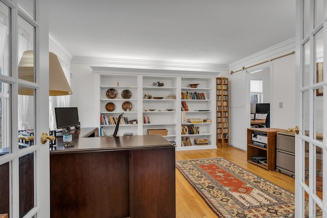 office featuring a barn door, ornamental molding, french doors, and light wood-style flooring