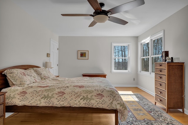 bedroom featuring light wood finished floors, a ceiling fan, and baseboards