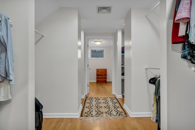 hall featuring visible vents, baseboards, and wood finished floors