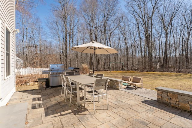 view of patio featuring outdoor dining space, exterior kitchen, fence, and grilling area