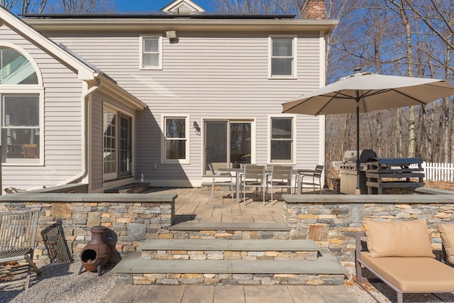 back of property featuring a patio area, a chimney, and fence